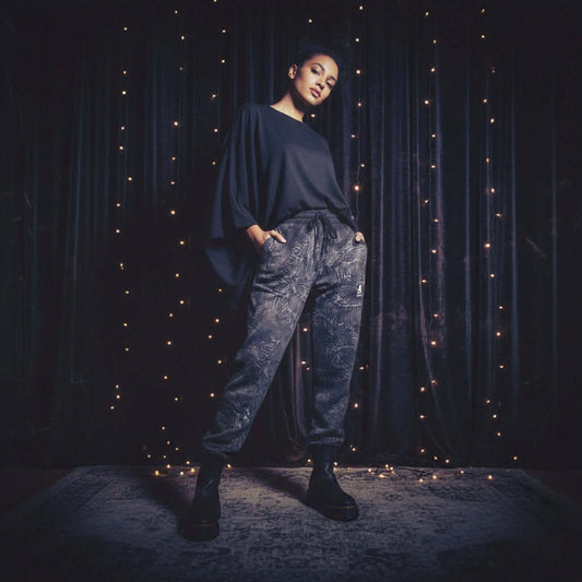 Model showcasing Scales Limited Edition Pants with elegant top against a backdrop of fairy lights.