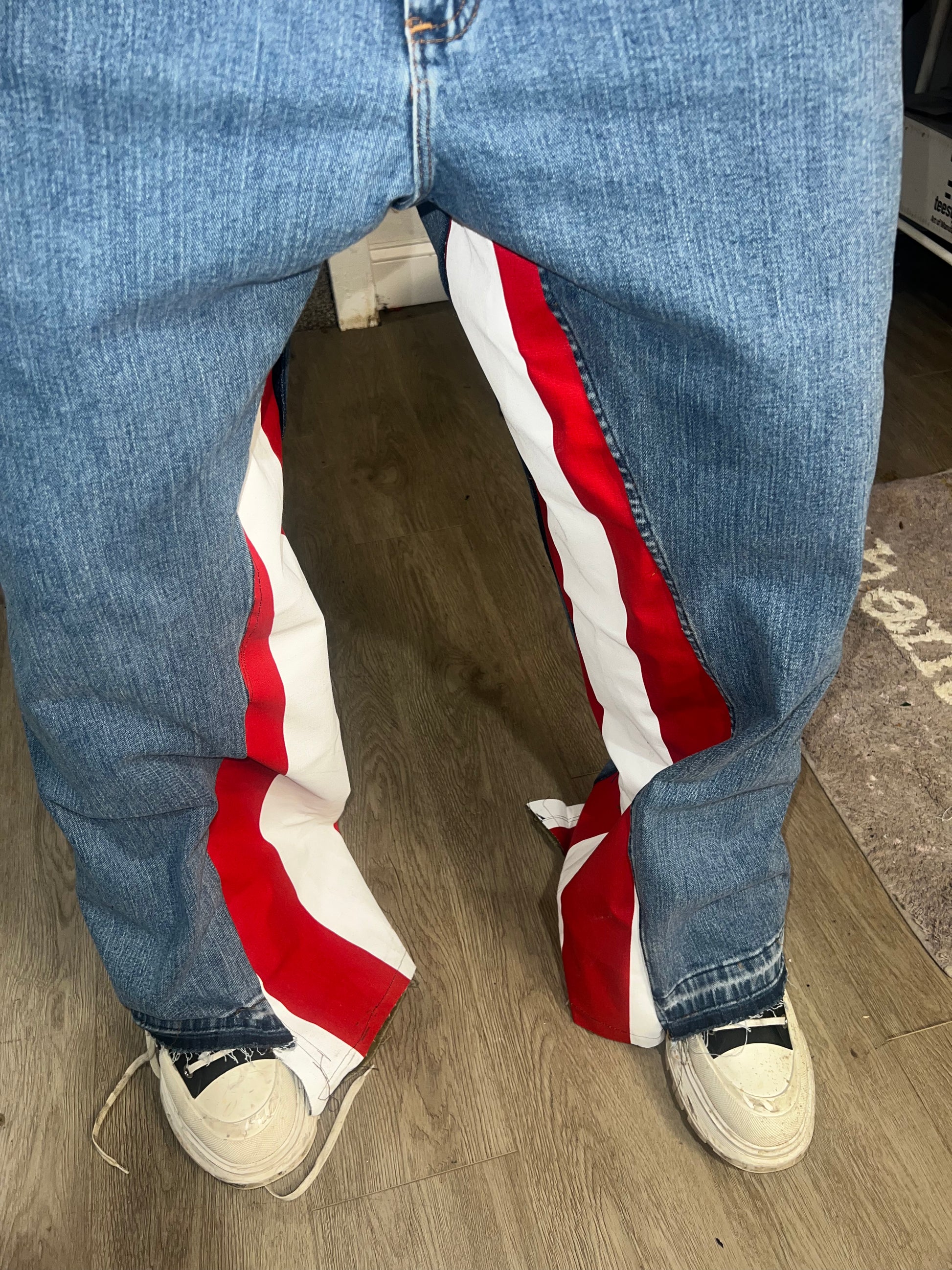 Blue jeans with a red, white, and blue patch on a wooden floor.