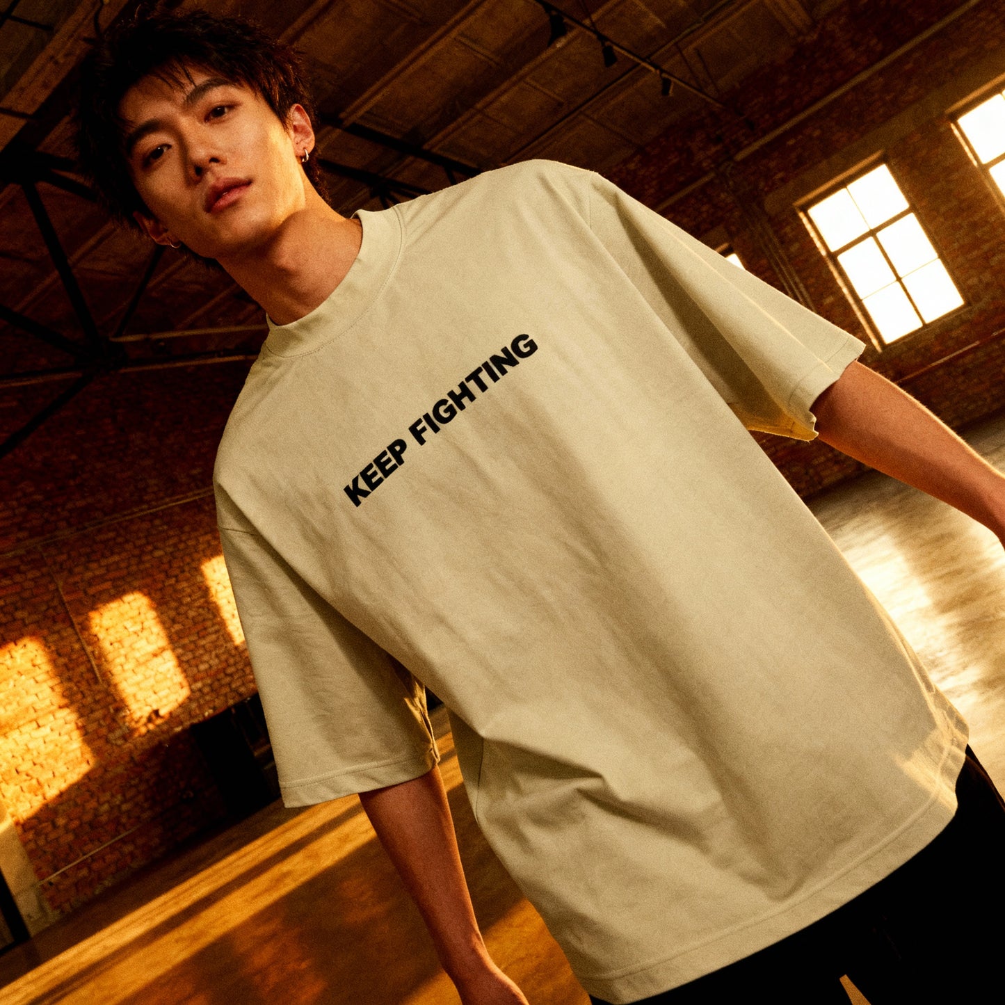 Person wearing a beige t-shirt with 'KEEP FIGHTING' text in a warm-lit indoor setting